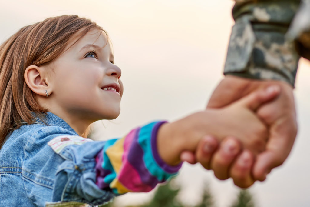 Close up portrait little girl looking at military father.