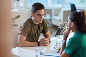 Young army soldier talking with doctor during his therapy.